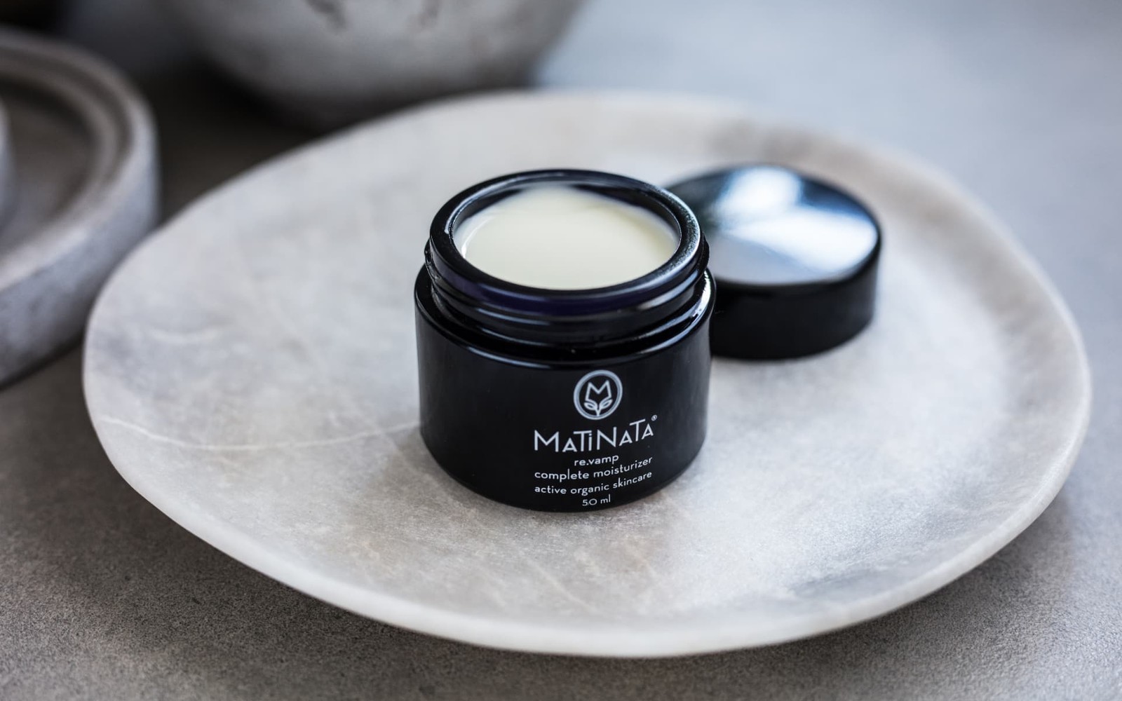 Award-recognised Matinata formulas in near-black glass on a pale stone dish