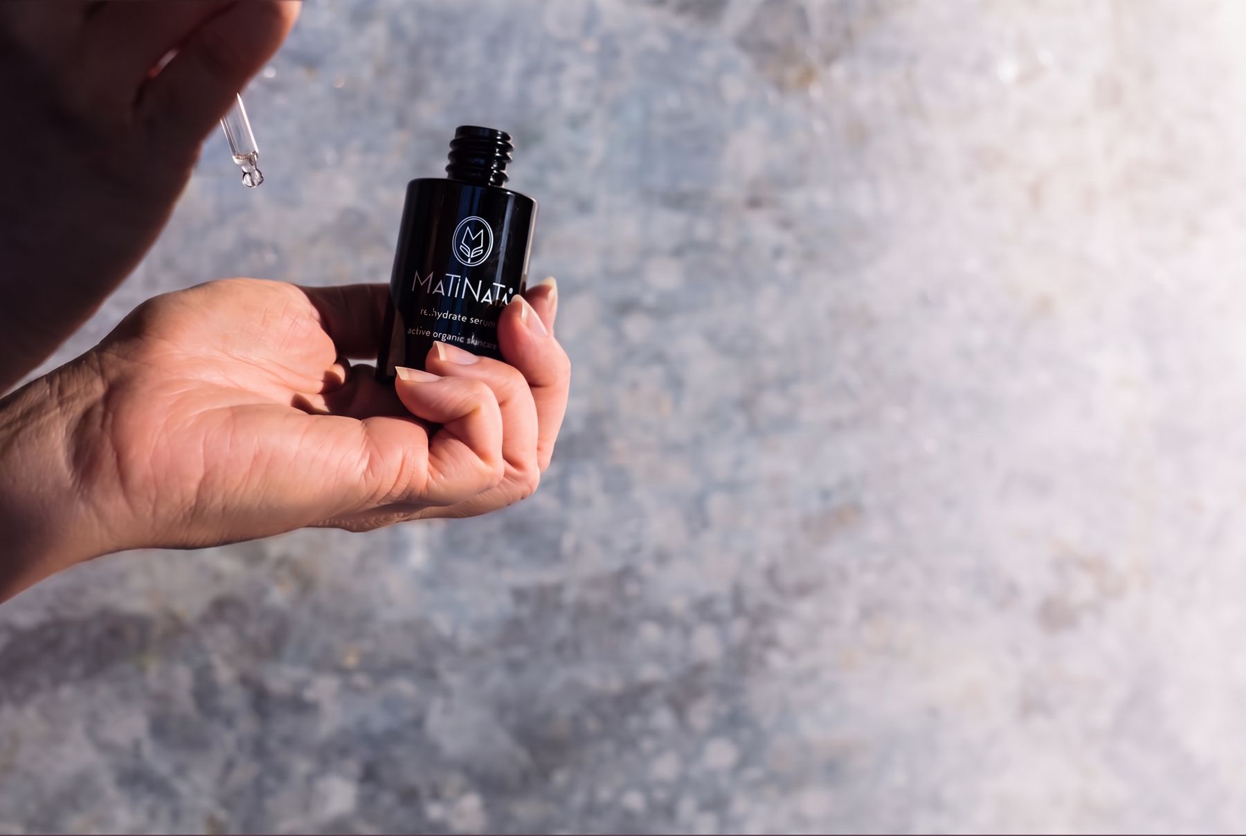 Matinata re.hydrate water serum held in hand with a dropper of clear serum