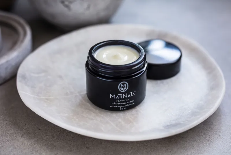 Matinata re.nourish rich renewal cream open on a marble plate, lid beside