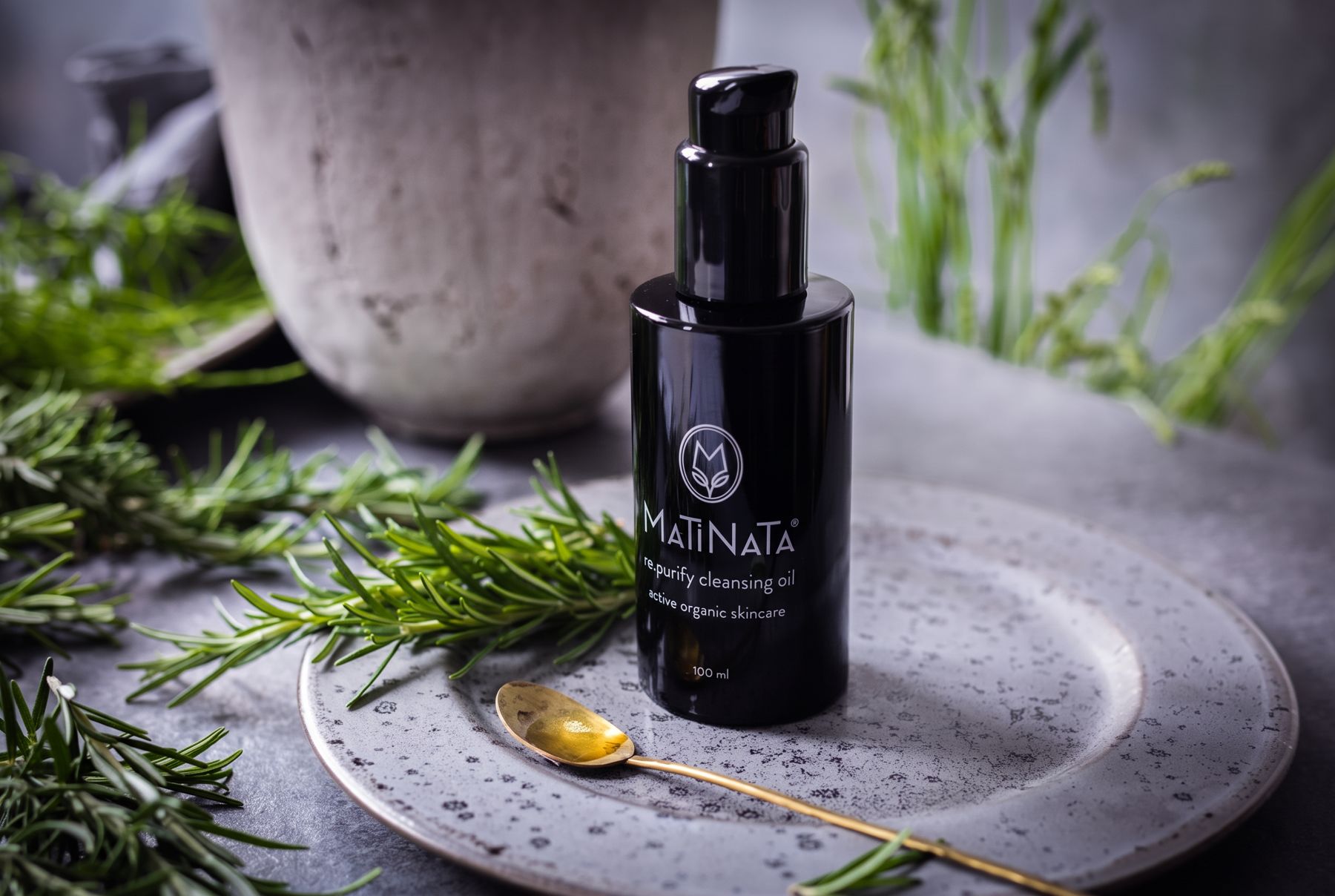 Matinata re.purify cleansing oil on a stone plate with fresh rosemary and a golden spoon of oil